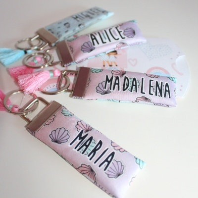 Chaveiros de tecido com nomes personalizados e padrão de conchas em tons pastel