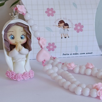 Terço decorativo branco e rosa com figura de Nossa Senhora com coroa prateada.