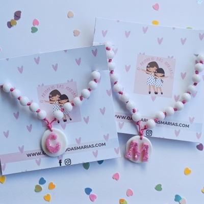 Colares de contas brancas com letras cor-de-rosa em cartões decorados com corações