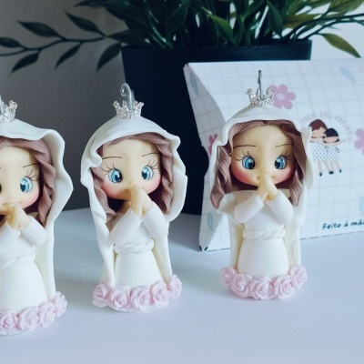Três figuras decorativas de meninas com capuz branco e coroas prateadas com rosas cor de rosa na base