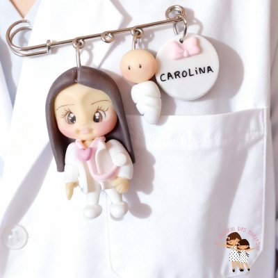 Alfinete com três pendentes de figuras em bolso branco