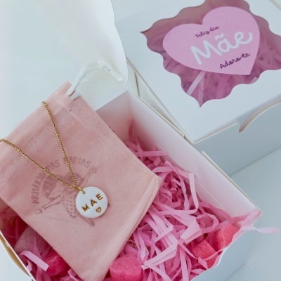 Colar com pendente redondo branco e inscrições a dourado MÃE com coração, em corrente dourada, embalagem branca com saco rosa e mensagem para o dia da mãe