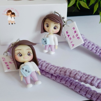 Dois porta-chaves em macramé lilás com bonecos de menina e etiquetas com nomes