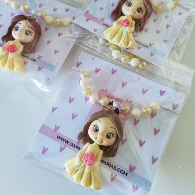 Colares com pendente de boneca em saco plástico com cartão decorado com corações rosa