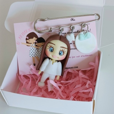 Prendedor com boneca e círculo decorativos dentro de caixa com papel cor-de-rosa