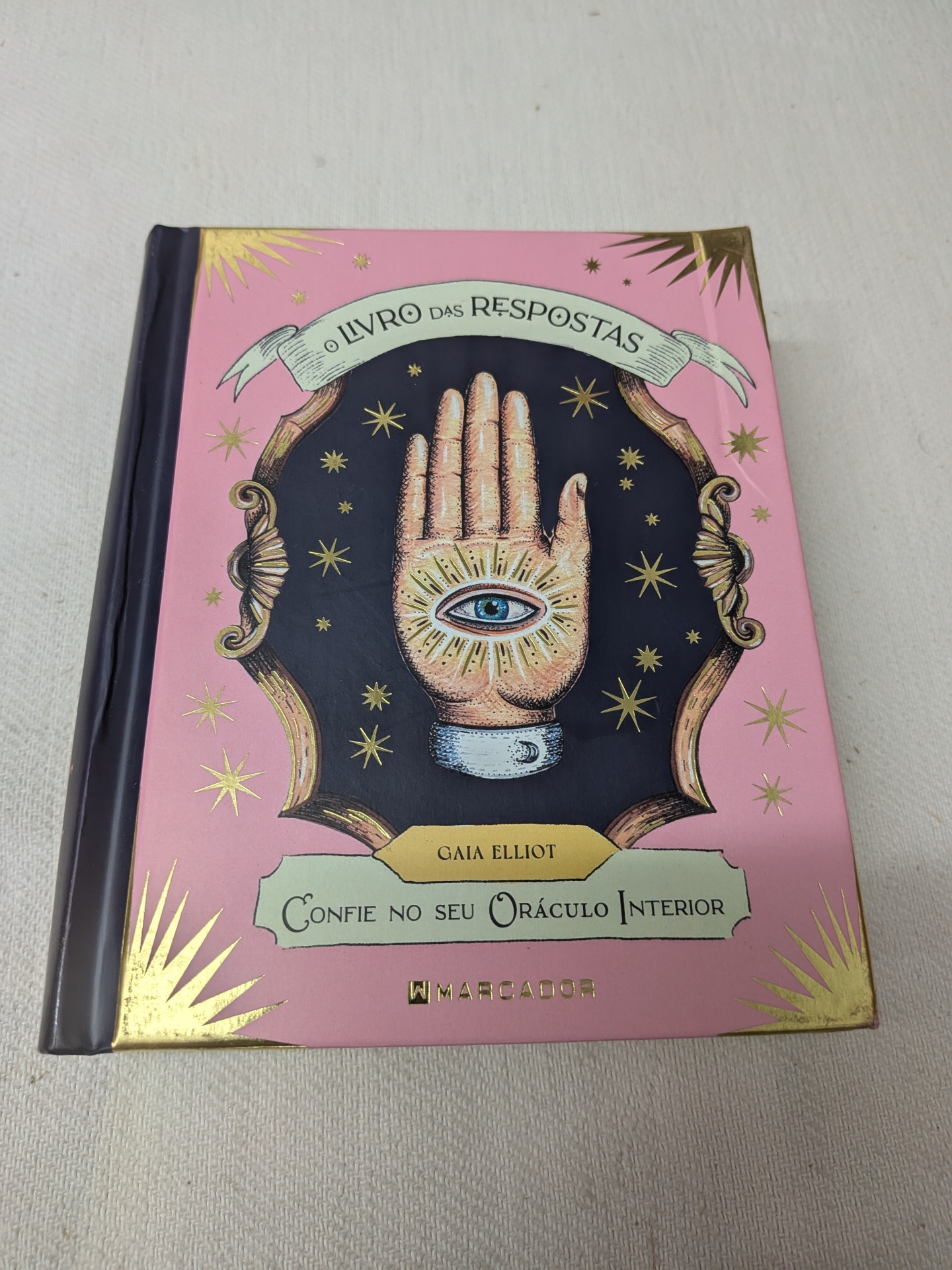 Gaia Elliot - O Livro das Respostas (defeito na capa) Livro com capa rosa, mão com olho azul e estrelas douradas