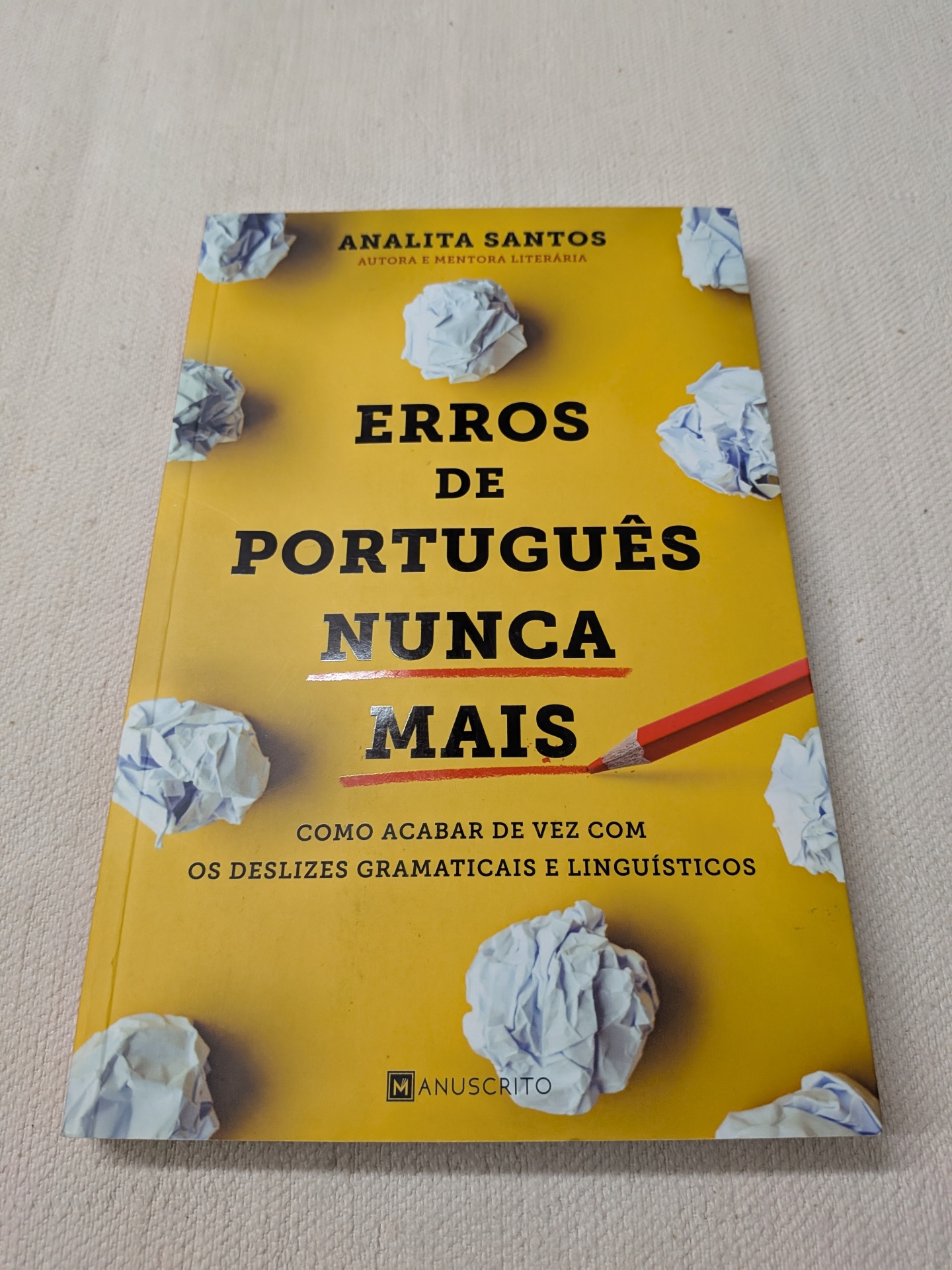 Analita Santos - Erros de Português Nunca Mais Livro amarelo Erros de Português Nunca Mais com bolas de papel amassado e lápis vermelho