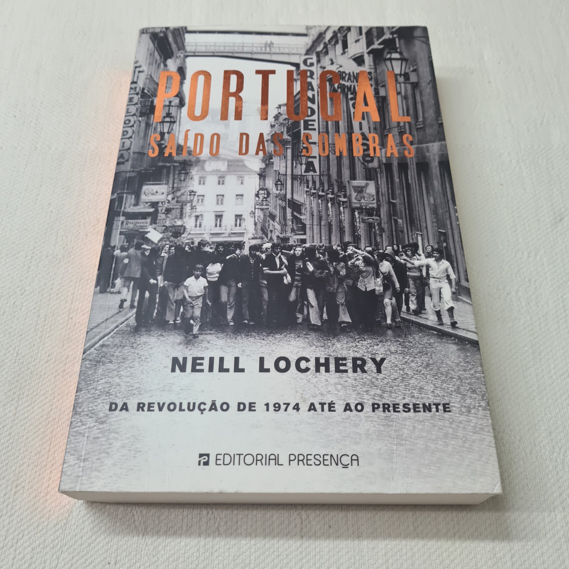Neill Lochery - Portugal - Saído das Sombras Livro 'Portugal Saído das Sombras' com capa em preto e branco e texto em laranja e preto