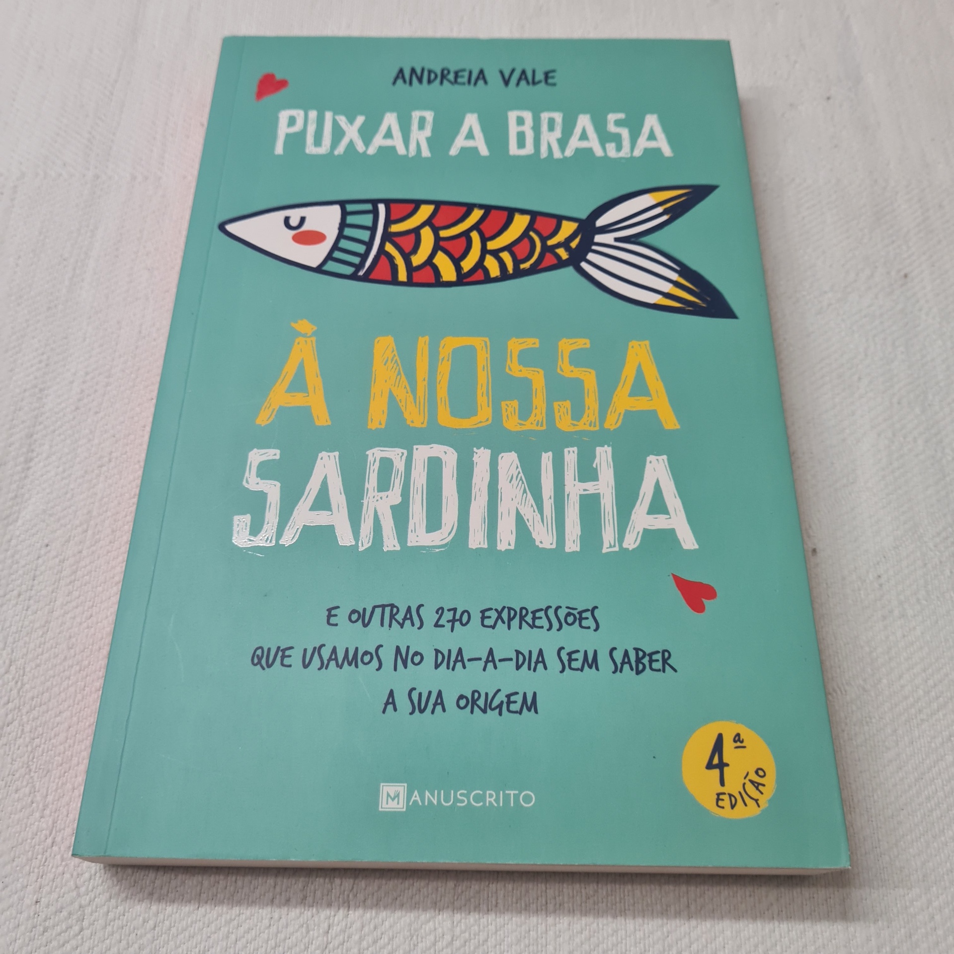 Andreia Vale - Puxar a Brasa à Nossa Sardinha Livro 'Puxar a Brasa À Nossa Sardinha' com capa verde, sardinha colorida e texto em branco e amarelo