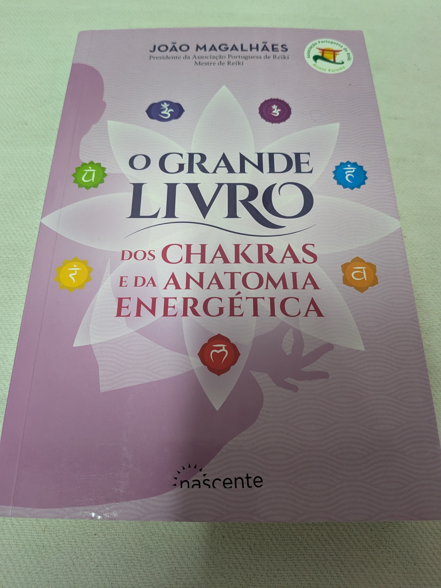 João Magalhães - O Grande Livro dos Chakras e da Anatomia Energética Capa de livro cor de rosa sobre chakras e anatomia energética com símbolos coloridos