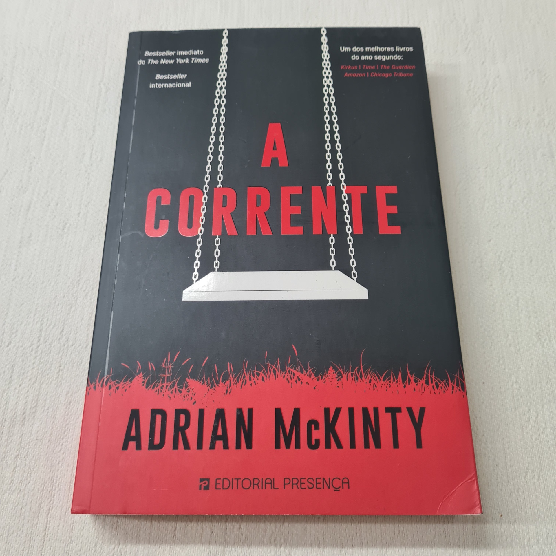 Adrian McKinty - A Corrente Capa do livro 'A Corrente' de Adrian McKinty com balanço branco e texto em vermelho e branco