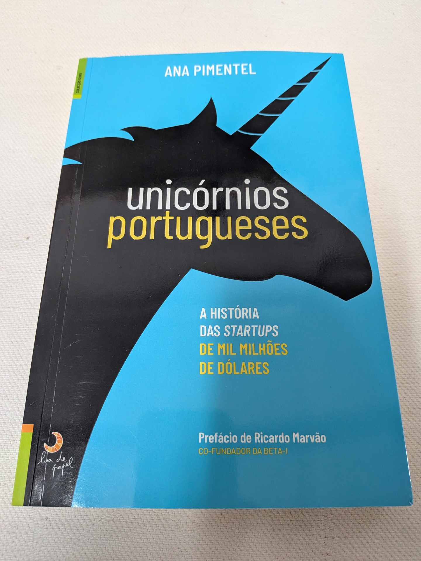 Ana Pimentel - Unicórnios Portugueses Capa de livro azul com ilustração de unicórnio preto e texto sobre startups portuguesas