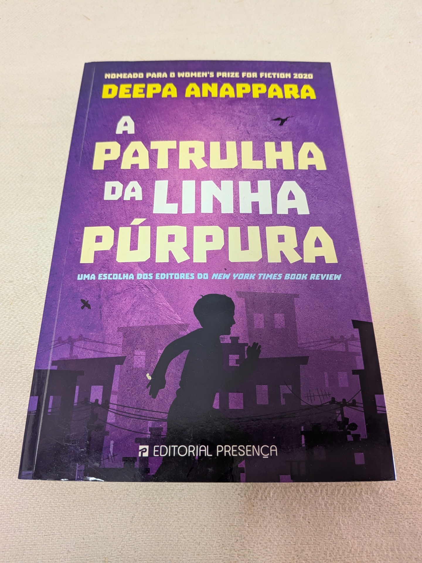 Deepa Anappara - A Patrulha da Linha Púrpura Capa de livro roxa com título em letras amarelas e brancas e silhueta de criança a correr