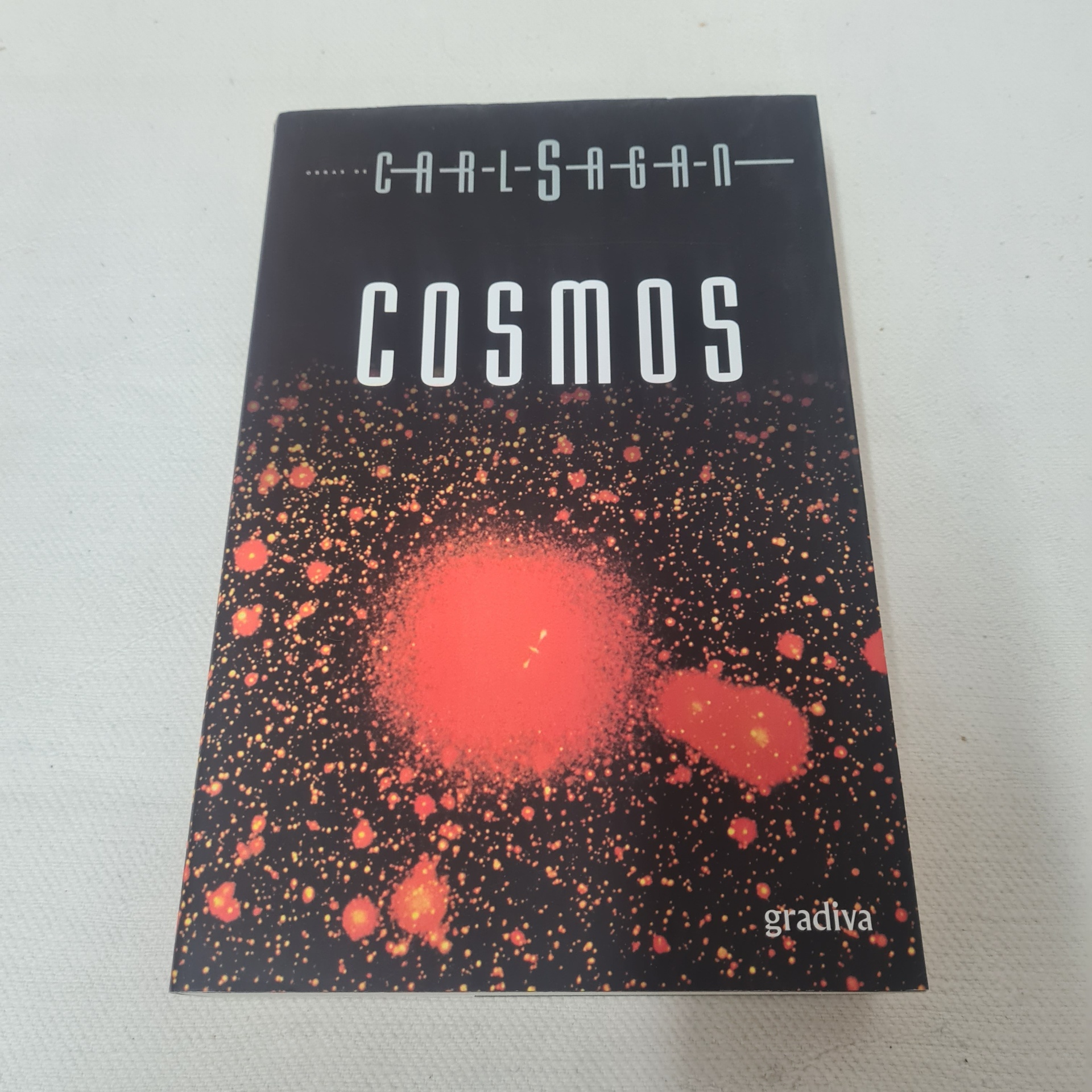 Carl Sagan - Cosmos Capa de livro 'COSMOS' de Carl Sagan com padrão vermelho e preto