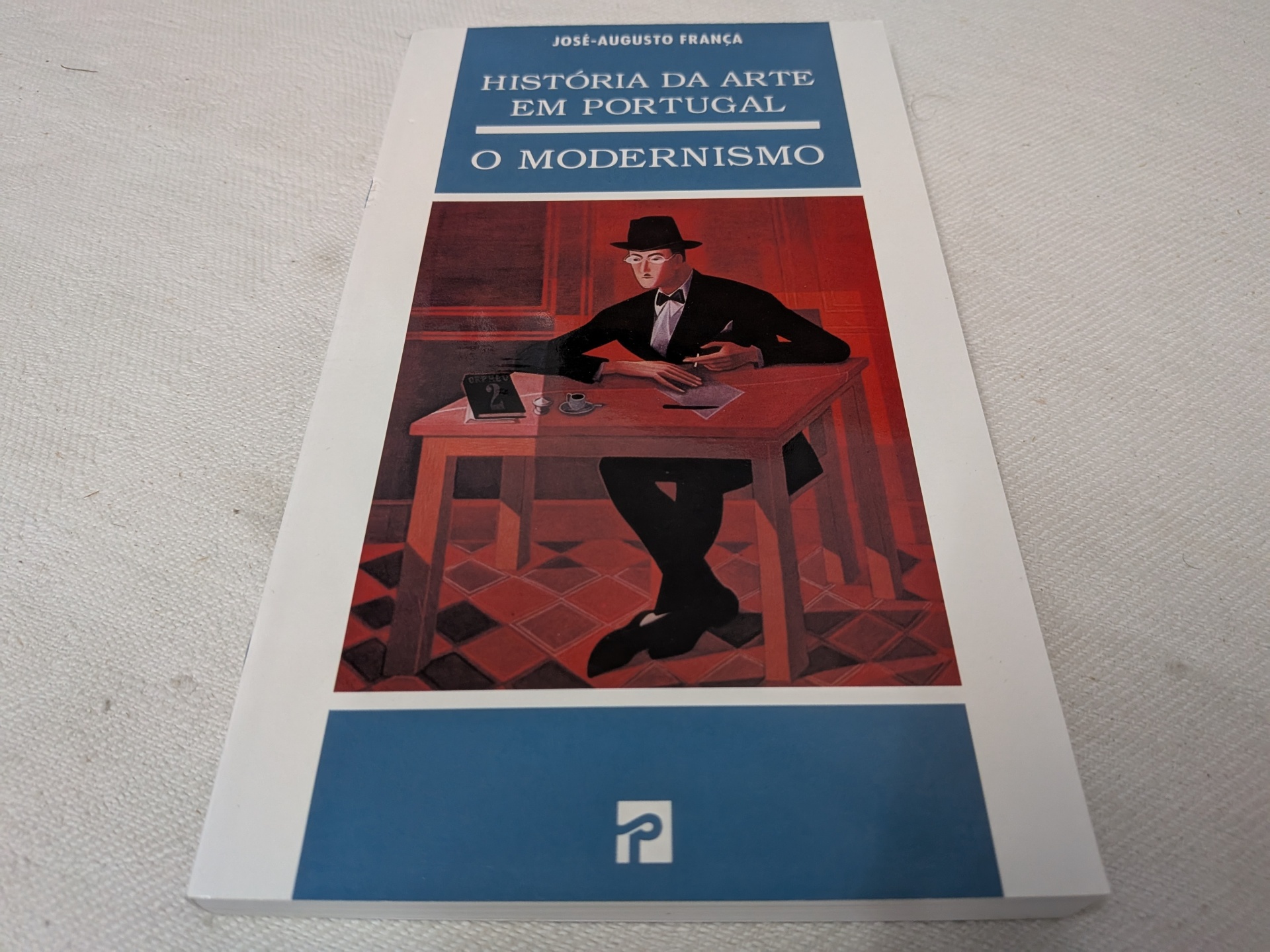 José-Augusto França - História da Arte em Portugal - O Modernismo Capa do livro 'História da Arte em Portugal: O Modernismo' com ilustração de um homem sentado numa mesa.