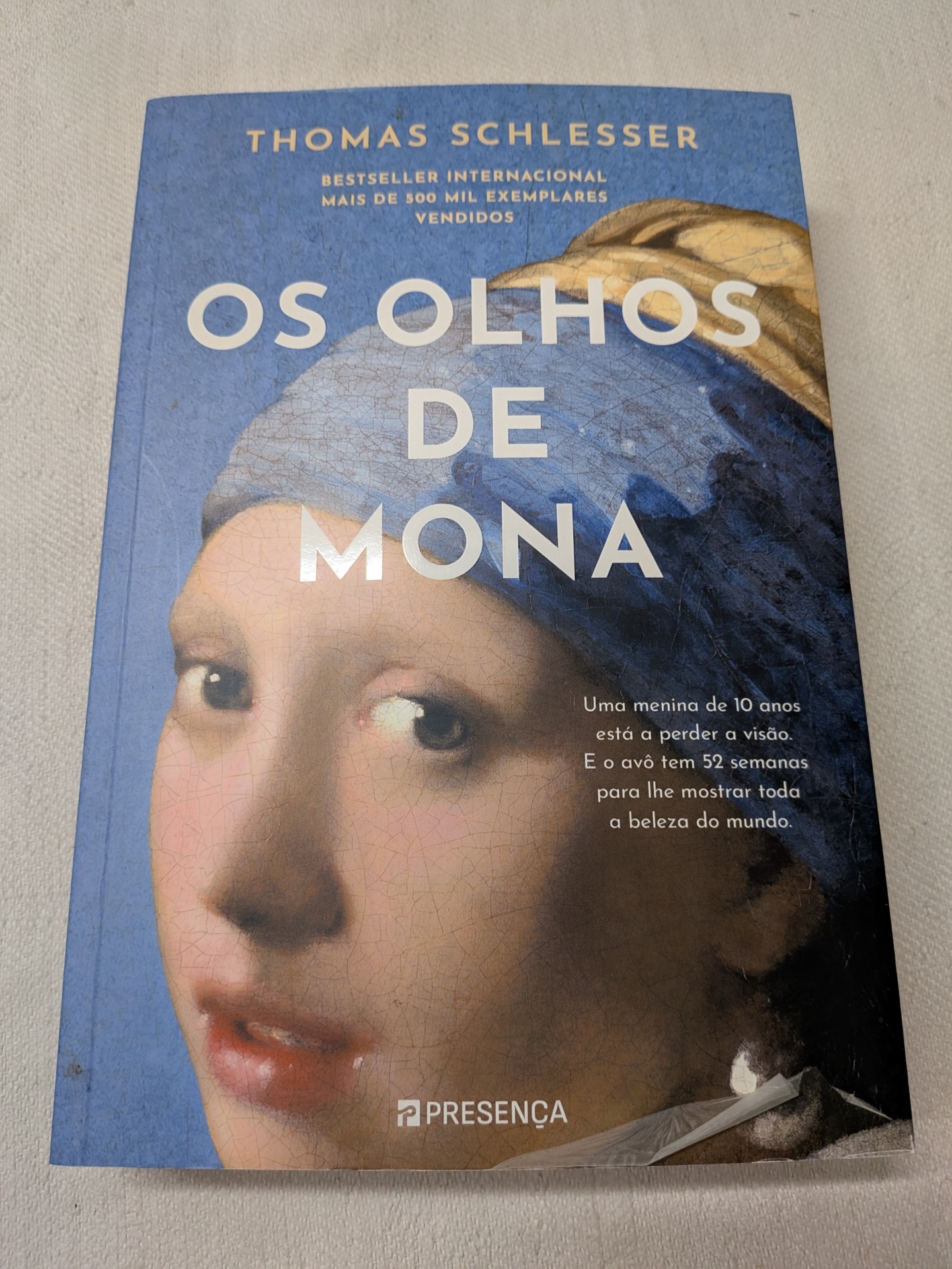 Thomas Schlesser - Os Olhos de Mona Capa de livro azul com imagem de pintura clássica e texto em português