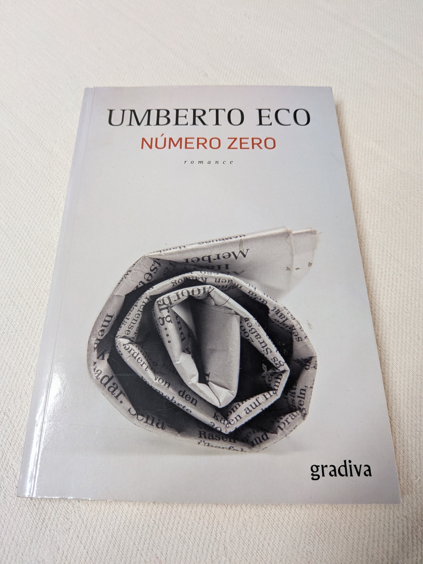Umberto Eco - Número Zero Capa do livro Número Zero de Umberto Eco com uma imagem de jornal enrolado em formato de rosa.