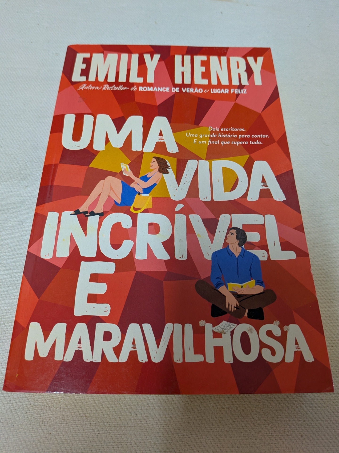 Emily Henry - Uma Vida Incrível e Maravilhosa Capa de livro vermelho com letras brancas e desenhos de homem e mulher a ler.