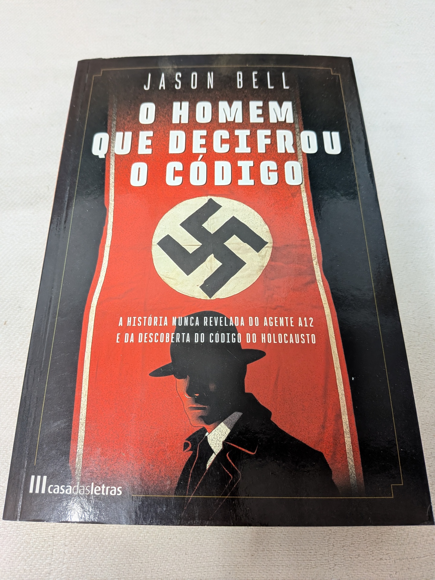 Jason Bell - O Homem que Decifrou o Código Capa do livro O Homem Que Decifrou o Código de Jason Bell com símbolo nazi e silhueta de homem