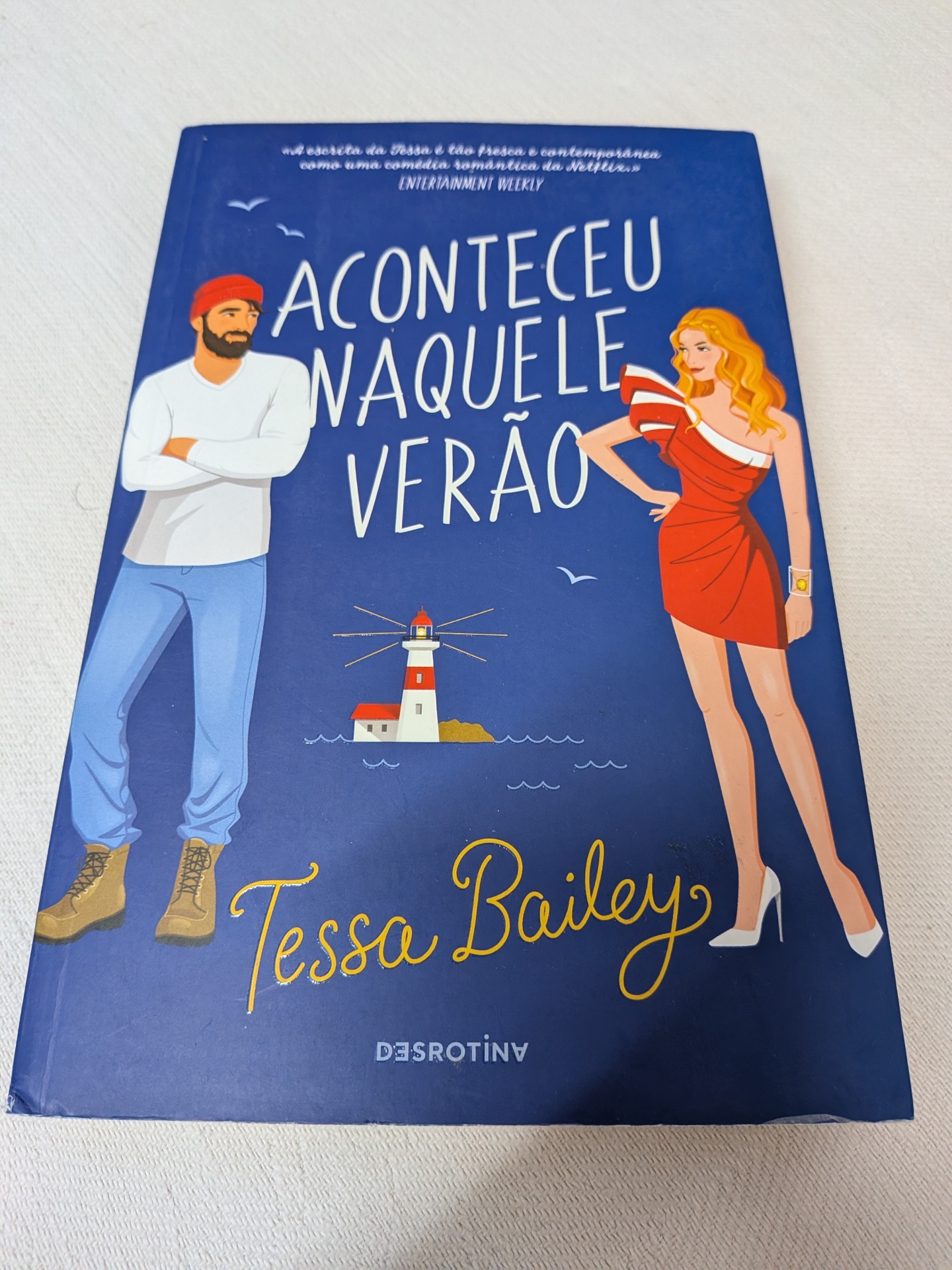 Tessa Bailey - Aconteceu Naquele Verão Capa de livro azul com ilustrações de homem e mulher e texto Aconteceu Naquele Verão