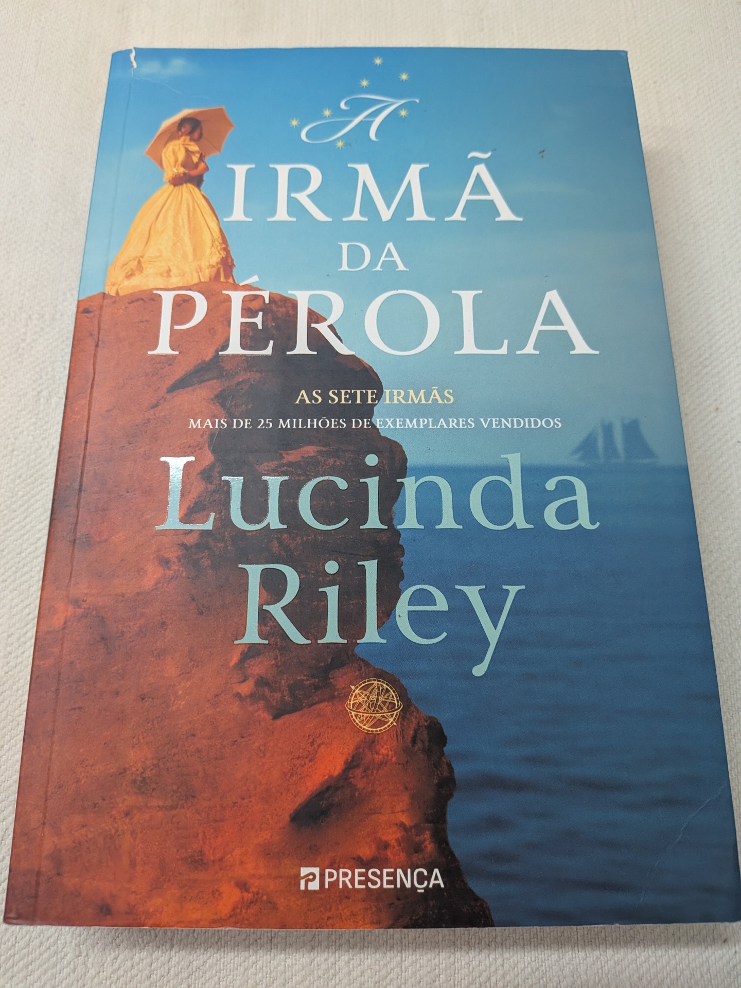 Lucinda Riley - As Sete Irmãs - A Irmã da Pérola (defeito na capa) Capa de livro A Irmã da Pérola de Lucinda Riley com mulher de vestido amarelo em rocha