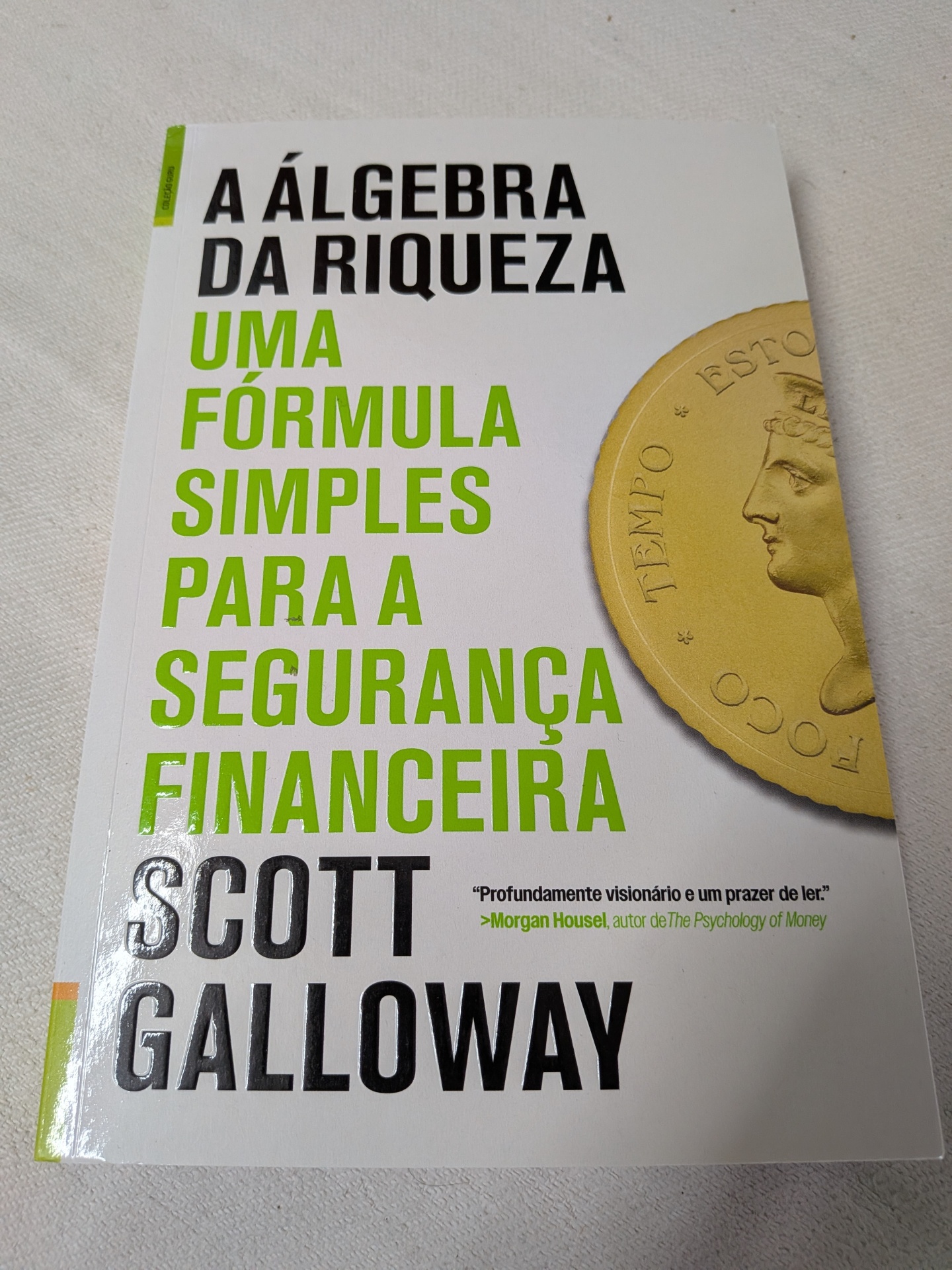 Scott Galloway - A Álgebra da Riqueza (Uma fórmula simples para a segurança financeira) Livro A Álgebra da Riqueza com capa branca e imagem de moeda dourada