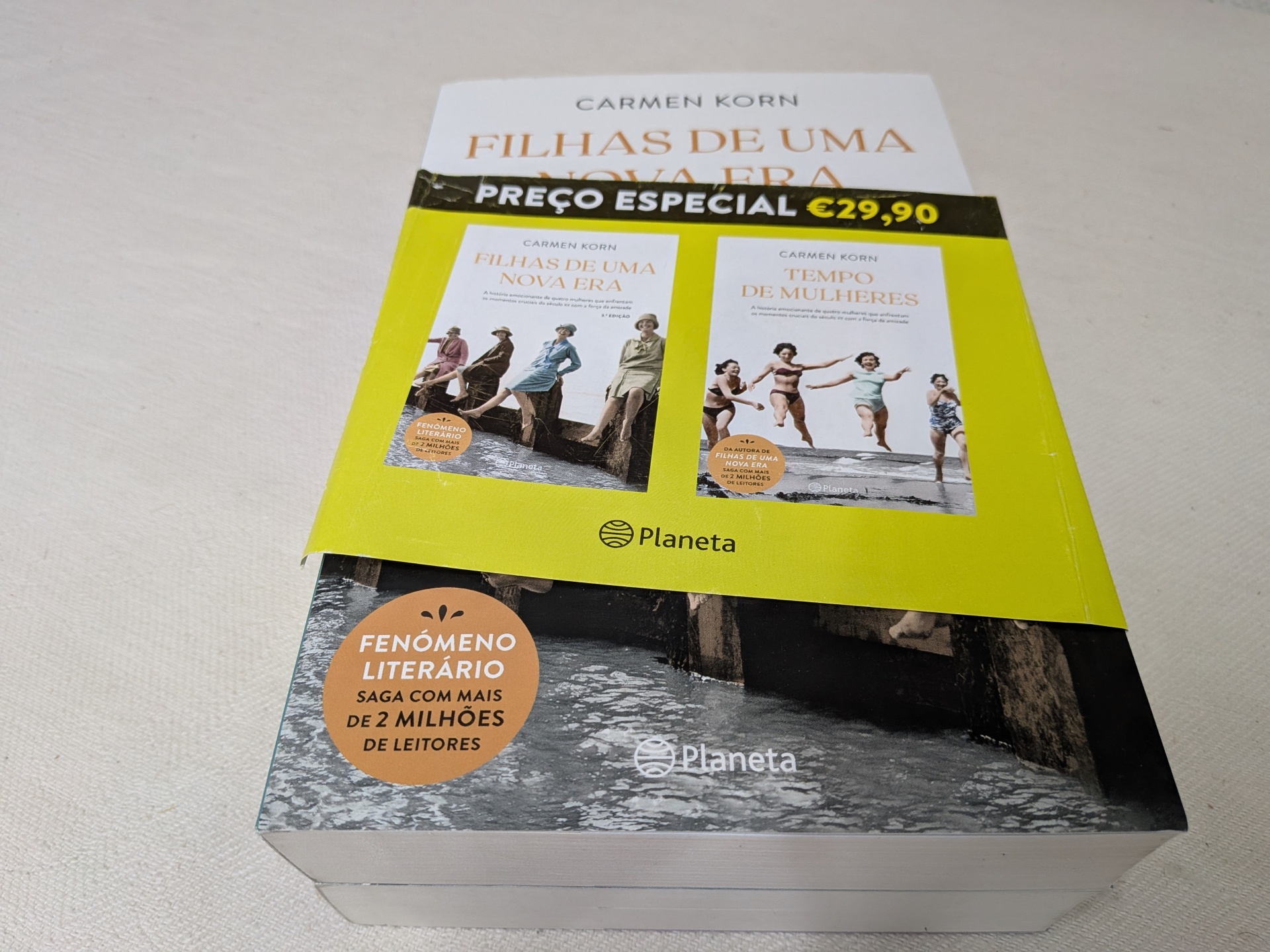 Carmen Korn - Pack - As Filhas de uma Nova Era | Tempo de Mulheres Caixa caixa com dois livros de capa dura, faixa amarela com preço especial €29,90, selo de fenómeno literário, fundo madeira e água.