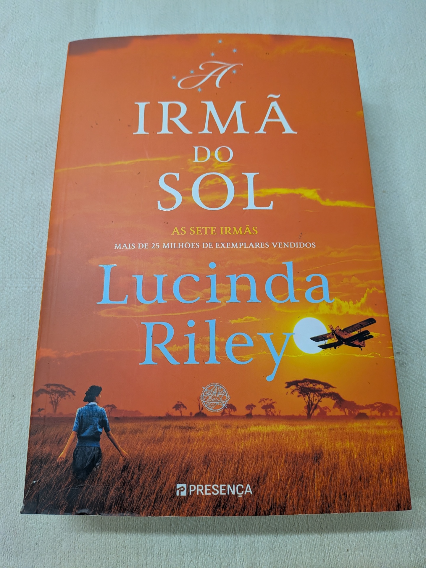 Lucinda Riley - As Sete Irmãs - A Irmã do Sol (A história de Electra) - defeito na capa Capa de livro laranja com texto e ilustração de pôr do sol