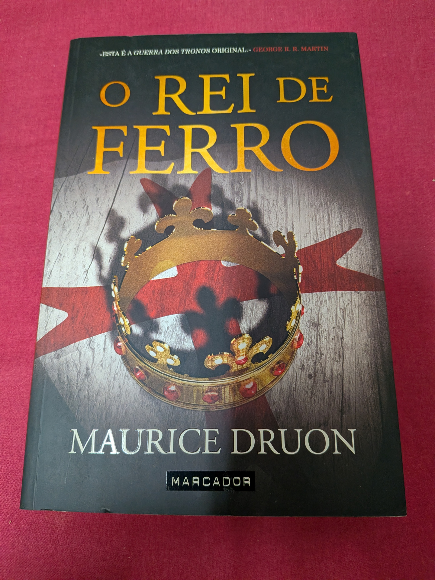 O Rei de Ferro de Maurice Druon Capa de livro O Rei de Ferro com coroa dourada e fundo vermelho.