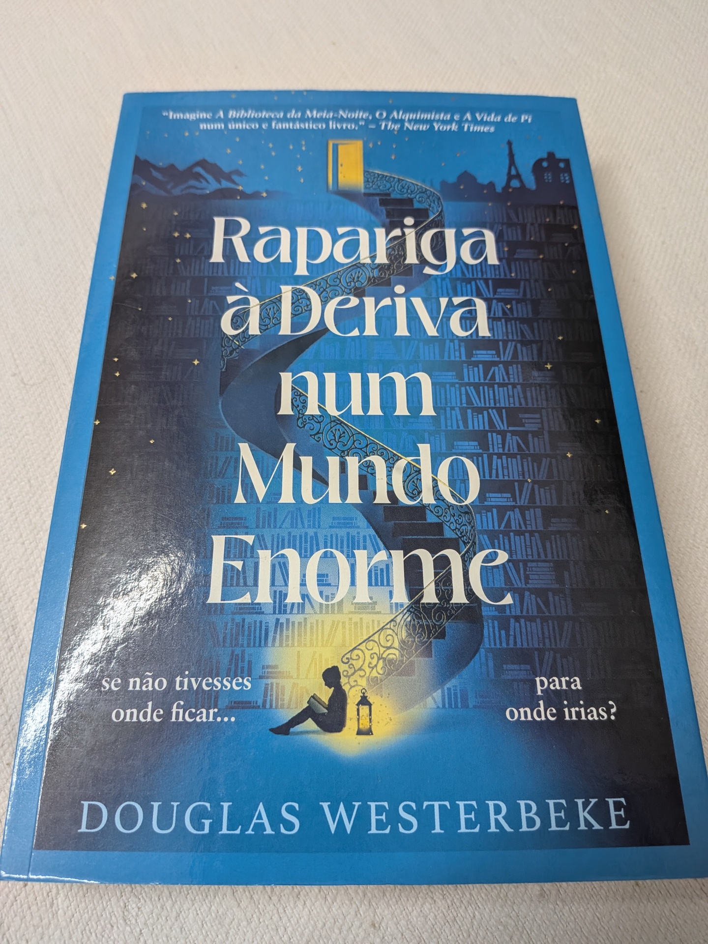 Douglas Westerbeke - Rapariga à Deriva Num Mundo Enorme Capa de livro azul com ilustração e título 'Rapariga à Deriva num Mundo Enorme'.