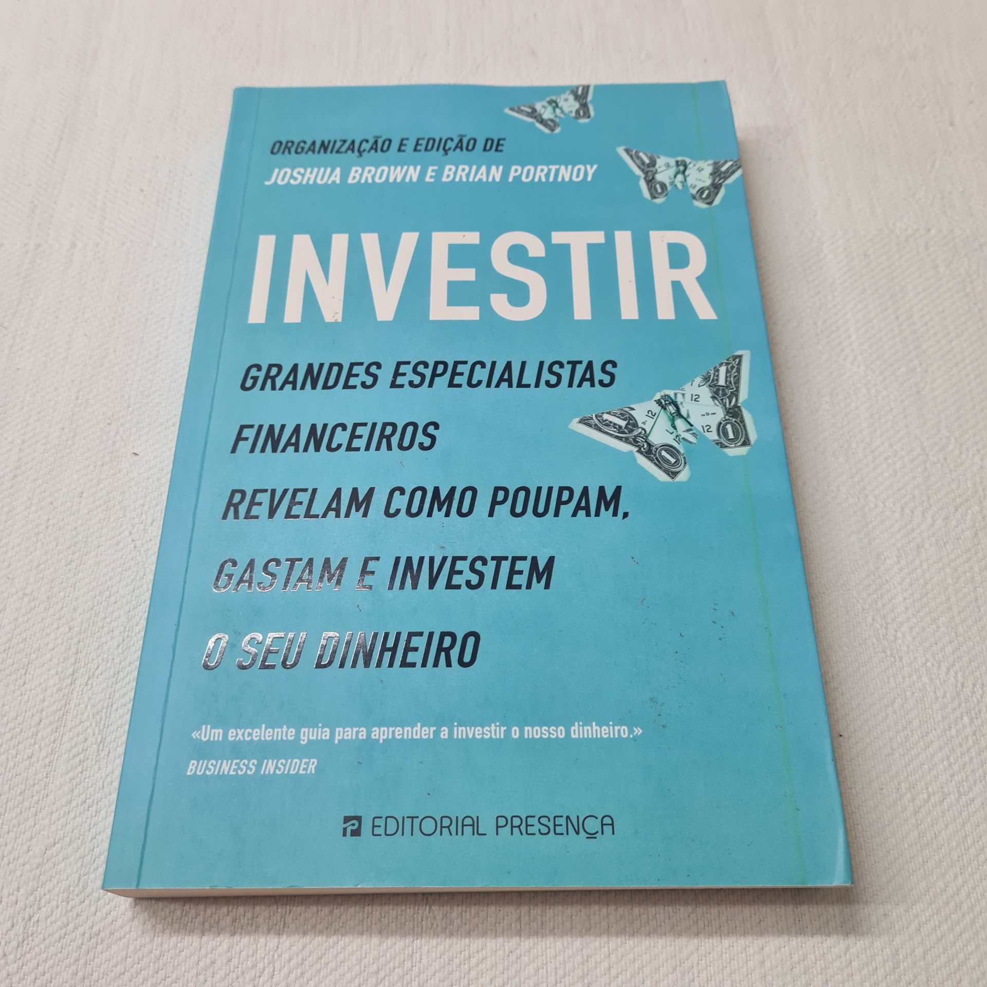 Joshua Brown e Brian Portnoy - Investir Livro azul intitulado INVESTIR com texto sobre finanças e borboletas desenhadas na capa