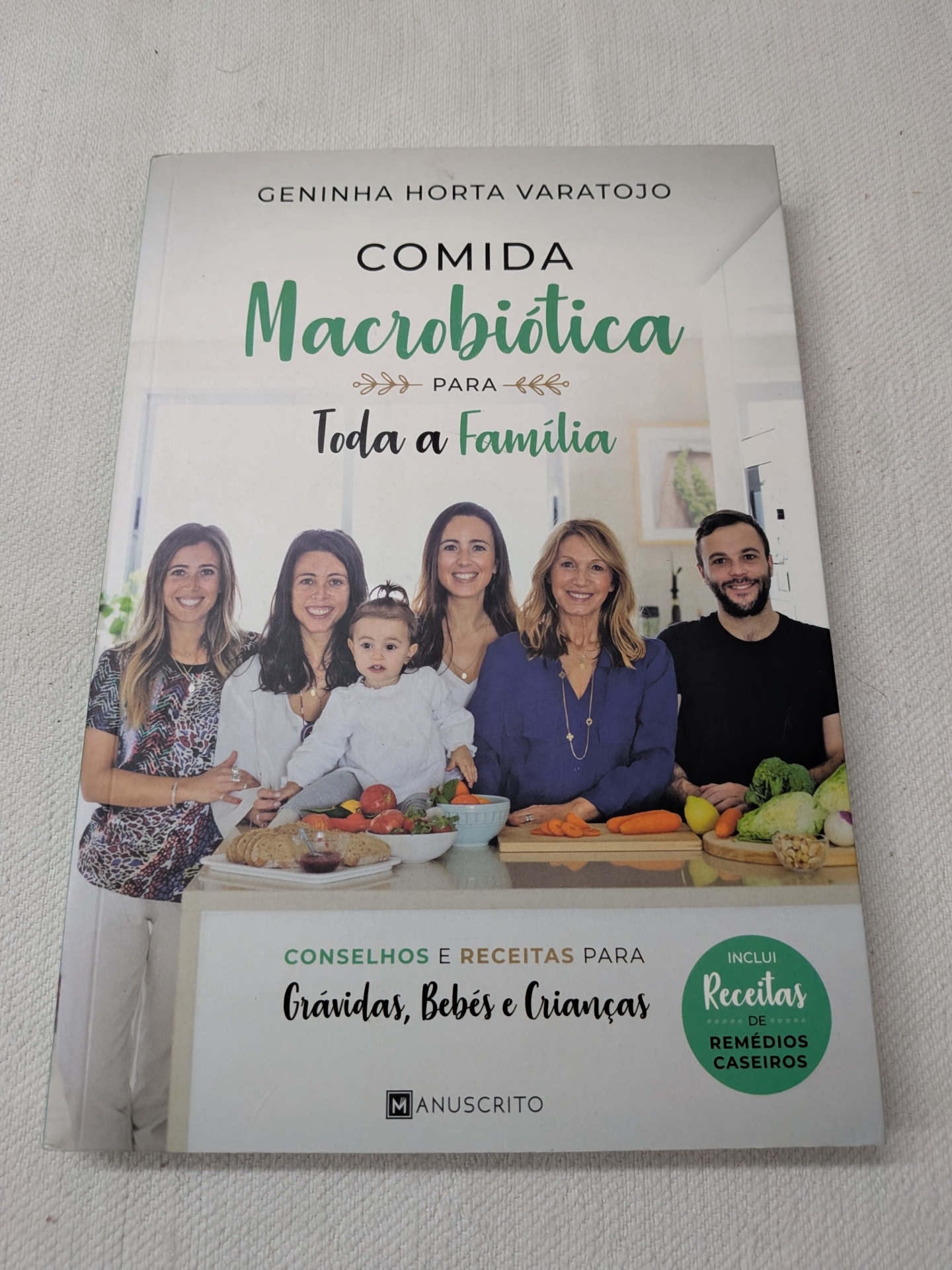 Geninha Horta Varatojo - Comida Macrobiótica para Toda a Família Capa de livro com cinco pessoas em cozinha e vários alimentos sobre balcão.