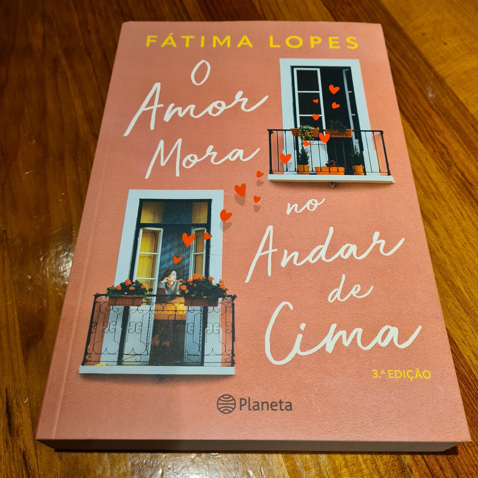 Fátima Lopes - O Amor Mora no Andar de Cima Capa de livro rosa com título e ilustrações de janelas com corações vermelhos