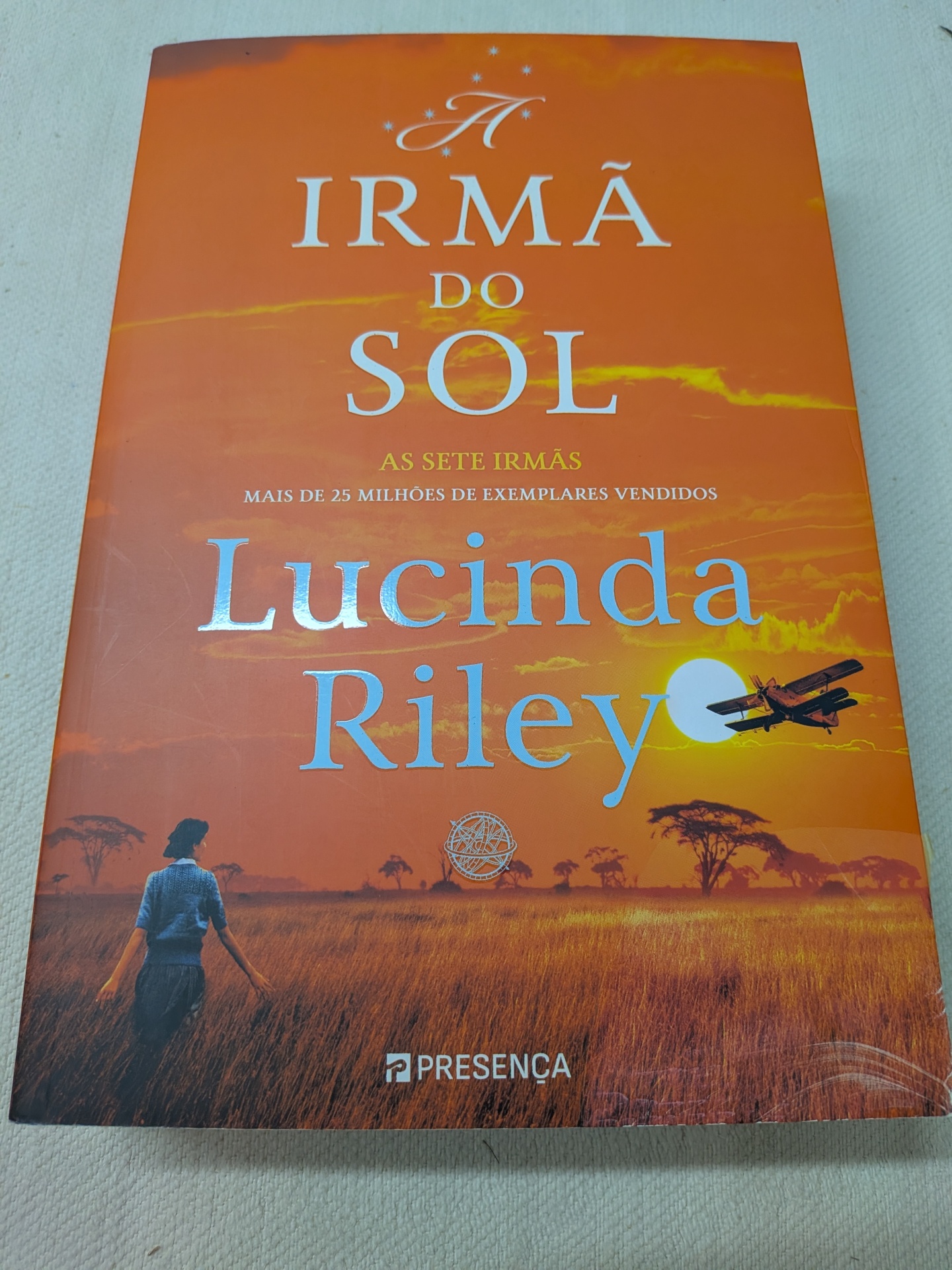 Lucinda Riley - As Sete Irmãs - A Irmã do Sol (A história de Electra) - defeito na capa Capa do livro A Irmã do Sol de Lucinda Riley em tons laranja com campo e pessoa de costas