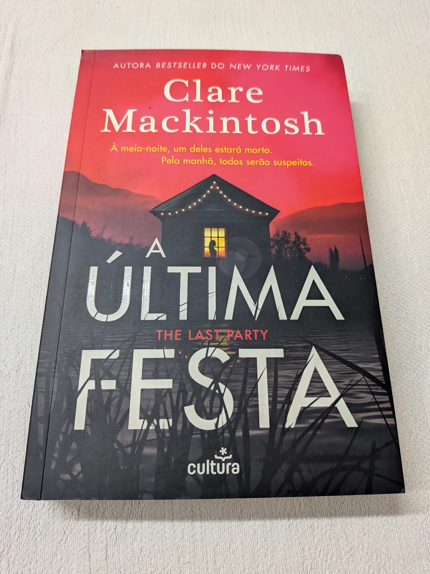 Clare Mackintosh - A Última Festa Capa de livro A Última Festa de Clare Mackintosh com fundo de casa iluminada e lago