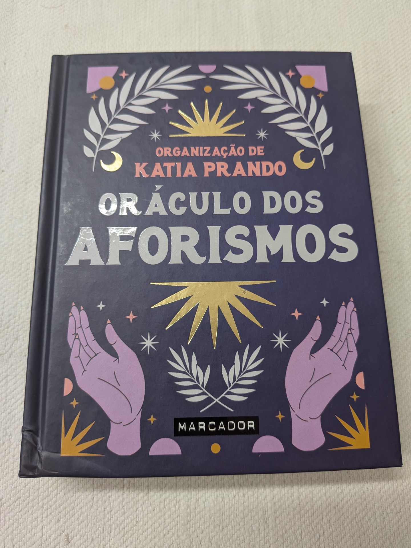 Katia Prando e Caterina Baldi - Oráculo dos Aforismos (defeito na capa) Capa de livro roxa com título e ilustrações em dourado e lilás