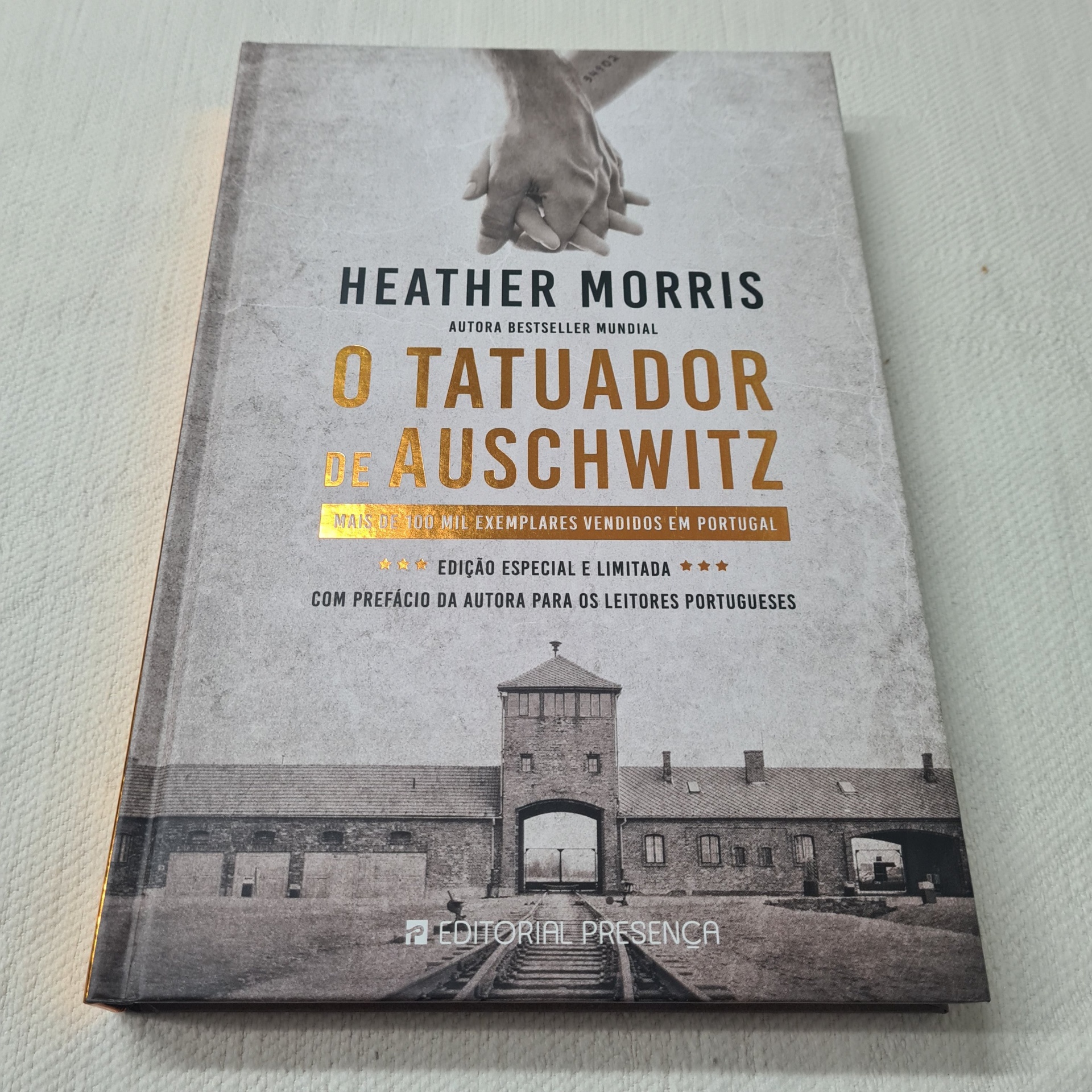 Heather Morris - O Tatuador de Auschwitz (Edição Especial e limitada) Livro O Tatuador de Auschwitz com capa cinzenta e foto do campo de concentração