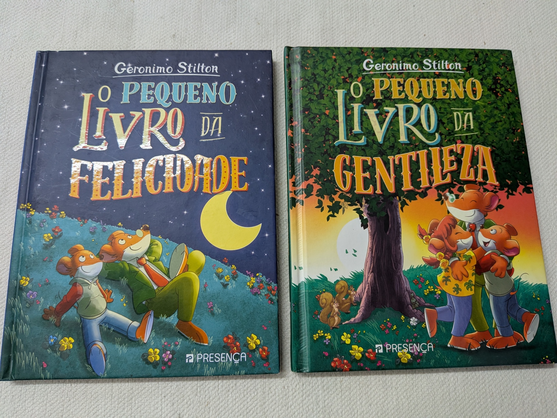 Geronimo Stilton - O Pequeno Livro da Gentileza + O Pequeno Livro da Felicidade Dois livros de capa dura infantis de Geronimo Stilton, títulos em letras coloridas, com ilustrações de ratos em ambientes naturais.