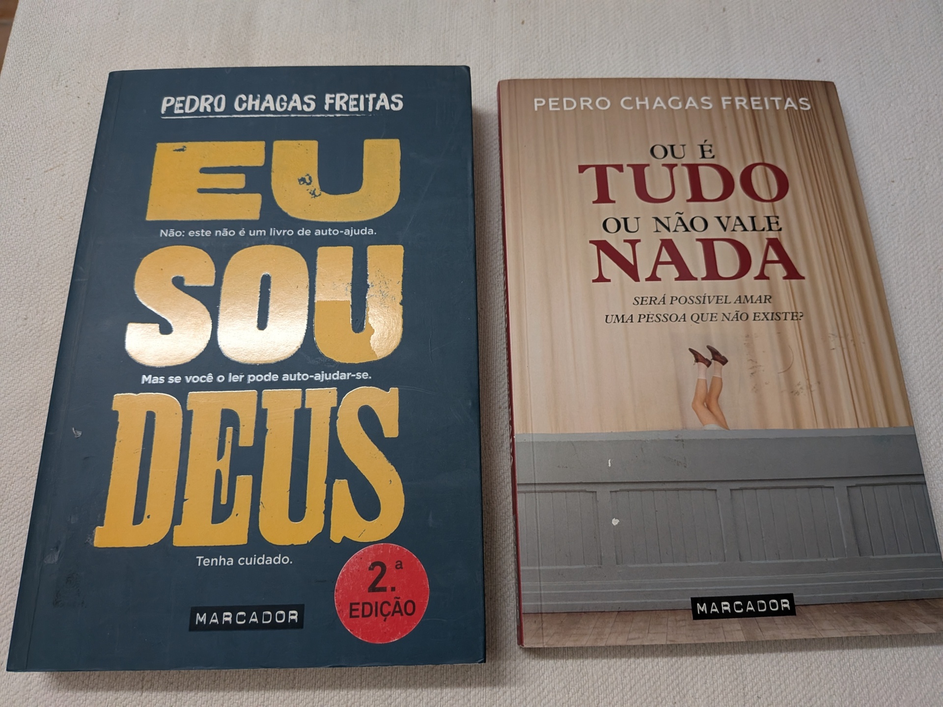 Pack Pedro Chagas Freitas - Eu Sou Deus + Ou é Tudo ou Não Vale Nada Dois livros de Pedro Chagas Freitas, um com capa azul e outro bege, sobre superfície clara.