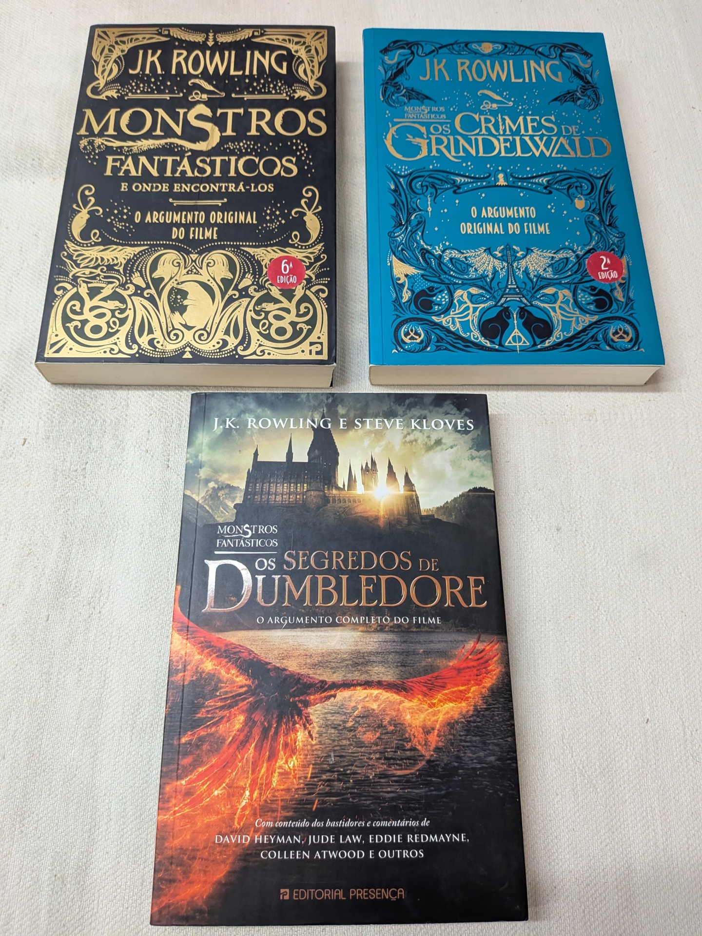 PACK J. K. Rowling - Monstros Fantásticos e Onde Encontrá-los + Os Crimes de Grindelwald + Os Segredos de Dumbledore Três livros de J.K. Rowling sobre Monstros Fantásticos e Dumbledore, com capas em preto, azul e ilustração de fogo.