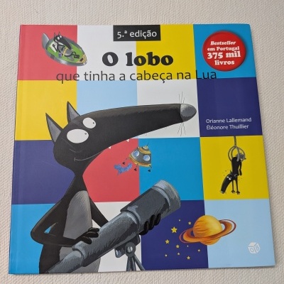 Capa do livro infantil O lobo que tinha a cabeça na Lua com ilustração de lobo e elementos espaciais em fundo colorido