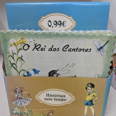 Conjunto de cartões ilustrados em caixa azul e bege com texto em português e preço visível.