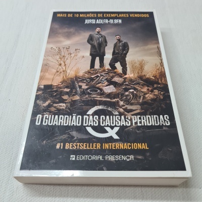 Capa do livro O Guardião das Causas Perdidas com duas pessoas num monte de lixo