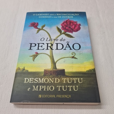 Capa do livro 'O Livro do Perdão' com flor vermelha e texto