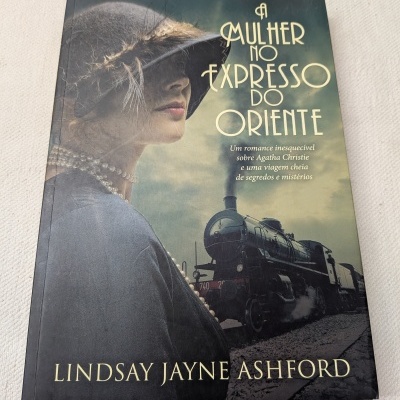 Capa do livro A Mulher no Expresso do Oriente com imagem de mulher de chapéu cinza e comboio a vapor