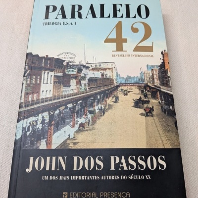Capa de livro com imagem antiga de cidade e linhas ferroviárias, texto em preto, dourado e branco.