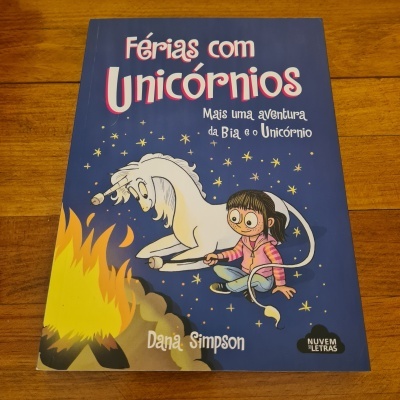 Capa de livro infantil com menina e unicórnio junto a fogueira
