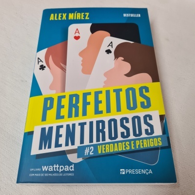 Capa de livro azul com cartas de baralho e título 'PERFEITOS MENTIROSOS'