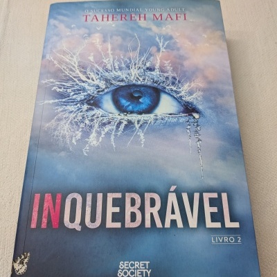 Capa do livro Inquebrável com olho azul e galhos brancos no fundo azul