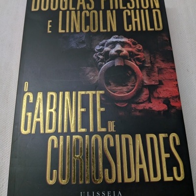 Capa de livro com título em letras douradas e imagem de cabeça de leão com argola